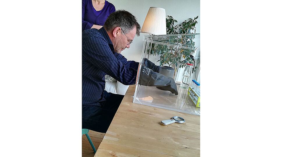 Mann versucht mit Handschuhen in einem Glascontainer Aufgaben zu lösen