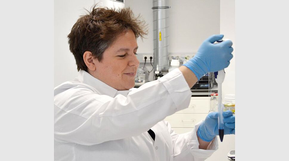 Das Bild zeigt die Mitgründerin Sabine Schmidhuber beim Pipettieren im Labor.