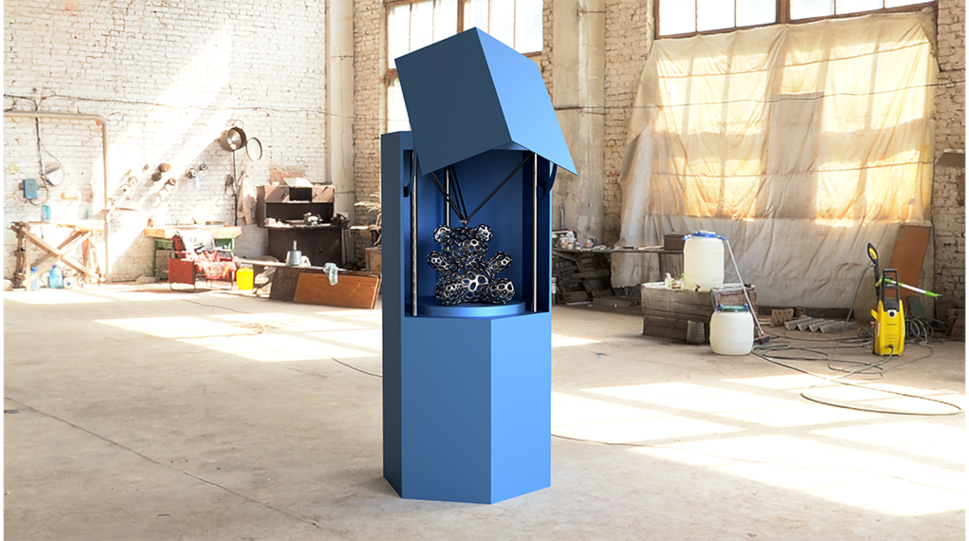 Das Bild zeigt ein circa 150 Zentimeter großes repräsentatives Metallgehäuse in Blau inmitten eines leeren Industriegebäudes. Im Inneren des Gehäuses sind mit PluriBot-Technologie gedruckte Metallteile künstlerisch angeordnet zu betrachten. © PluriBot