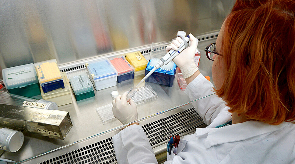 Eine Frau befüllt ein Reagenzglas in einem Labor
